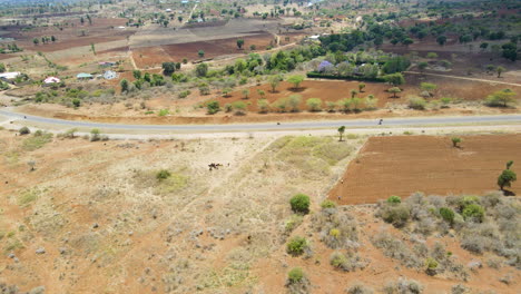 Impresionante-Antena-De-Edificios-Al-Lado-De-Un-Camino-Tranquilo-En-La-Zona-Rural-De-Kenia---Drones-Volando-Hacia-Atrás-Sobre-Suelo-Seco-Y-árido-Con-Caminos-De-Tierra