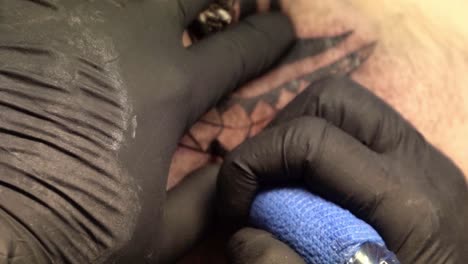 Tattoo-artist-coloring-the-tattoo-with-a-blue-needle-machine