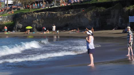 Menschen,-Die-An-Einem-Sonnigen-Sommertag-Am-Strand-Von-Playa-De-Las-Americas-Warmes-Wetter-Und-Den-Atlantik-Genießen,-Mittlerer-Handschuss