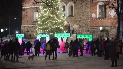 People-admiring-a-large-glowing-love-sign-in-front-of-a-church