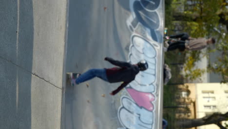 Vertical-video-of-young-kid-skater-drops-in-on-a-ramp-with-his-skateboard