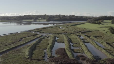 Aerial-flight-over-flooded-man-made-mounds-on-river-at-Waterford,-IRL