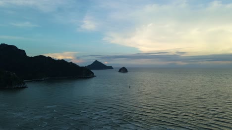 Wunderschöner-Sonnenuntergangshimmel-In-Blautönen,-Der-Den-Ozean,-Die-Insel-Und-Die-Berge-Als-Silhouette-Enthüllt