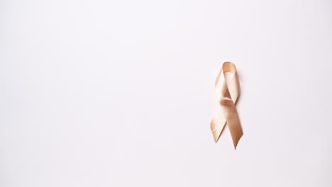 Detail-of-male-hand-holding-ribbon-in-orange-color-on-white-background