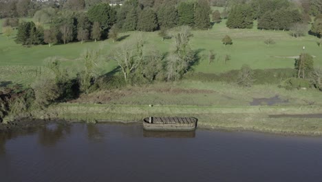 Retreating-aerial:-Rusty-river-barge-on-shore-by-Waterford-Golf-Resort