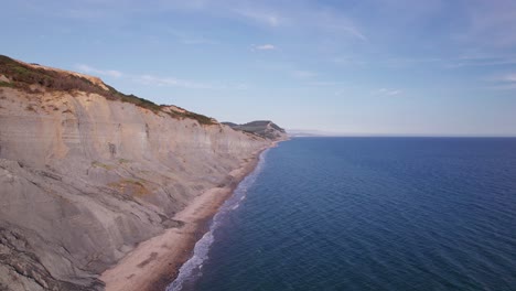 High-drone-shot-moving-upwards-showing-the-cliffs-on-the-Jurassic-Coast-on-a-summer-day,-Dorset,-UK