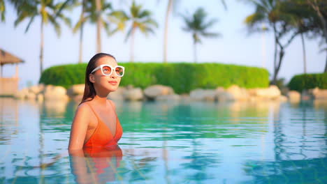 Young-Petite-Exotic-Woman-in-Swimming-Pool-at-Tropical-Paradise-on-Sunny-Day