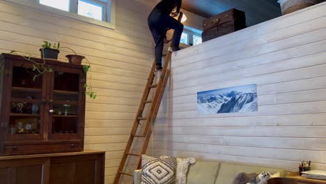 Young-white-male-climbing-down-wooden-ladder-in-ski-cabin-with-white-wooden-shiplap-walls
