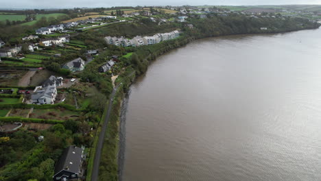 Aerial-View-of-Kinsale-Riverfront-on-Brandon-River,-Ireland,-Residential-Houses-and-Green-Coast-on-Moody-Autumn-Day,-Drone-Shot
