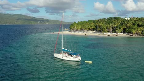 Aerial-circling-around-isolated-sailboat-moored-on-emerald-waters-near-Cayo-Levantado-in-Dominican-Republic