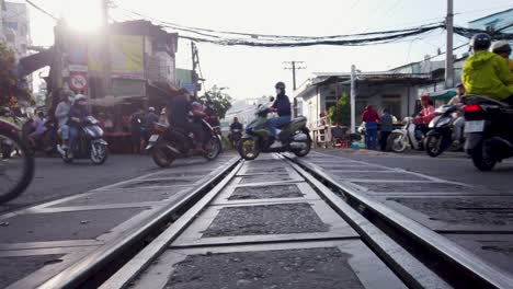 Motorcycle-traffic-over-train-tracks-on-a-level-crossing-in-Saigon-looking-into-light-from-a-low-angle
