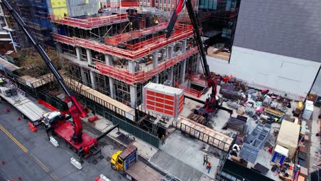 Aerial-view-following-a-crane-lifting-material-to-a-urban-construction-site-in-NY