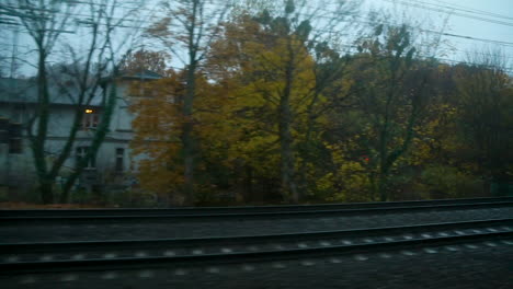 Blick-Auf-Herbstliche-Bäume-In-Der-Nachbarschaft-Aus-Dem-Fenster-Eines-In-Der-Abenddämmerung-Fahrenden-Zuges