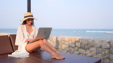 A-beautiful-Woman-Freelancer-Working-Using-Laptop-Sitting-on-Deckchair-By-the-Sea