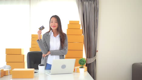 Asiatische-Frau,-Kleinunternehmerin-In-Ihrem-Büro,-Die-Bankkreditkarte-Zeigt,-Die-Kamera-Betrachtet