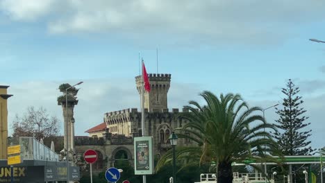 Weite-Ansicht-Des-Schlosses-Mit-Portugiesischer-Flagge-Am-Strand-In-Estoril,-Portugal