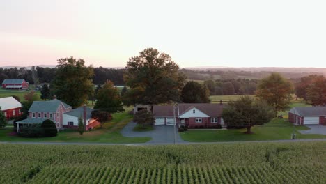 Aerial-establishing-shot-of-rancher-homes-in-rural-America-during-summer-sunset,-golden-hour-light
