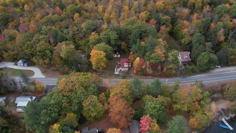 Aerial-View-of-Traffic-on-Coastal-Road-by-Lake-Sunapee,-Colorful-Fall-Foliage-and-Lakefront-Houses,-Drone-Shot