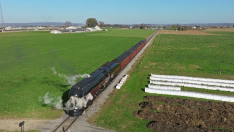 Drone-View-of-a-Steam-Passenger-Train-Blowing-Lots-of-Smoke-and-Steam-Standing-Still-on-a-Sunny-Fall-Day