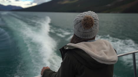 Female-on-Back-of-Ferry-Boat-Looking-at-Water-Wakes-and-Scenic-Coastline-of-Lake-Maligne,-Jasper-National-Park,-Canada,-Cinematic-Full-Frame-Shot