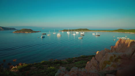 Cinemagraph-seamless-video-loop-of-sailing-boat-on-the-tourist-vacation-island-Sardinia-in-Italy-by-sunset-at-an-idyllic-sandy-beach-bay-with-turquoise-and-calm-water-close-to-Isola-Tavolara-and-Olbia
