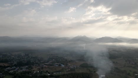 Sunshine-through-clouds-during-sunrise-above-foggy-village-in-the-Northern-Thailand
