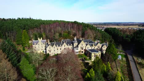 Stunning-aerial-of-Findhorn-foundation-Cluny-hill-castle,-zoom-out-reveal