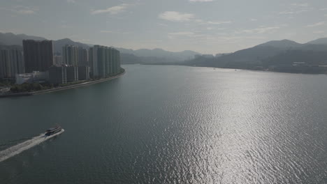 Aerial-pan-shot-of-boats-floating-and-skyscrapers-in-Hong-Kong,-China