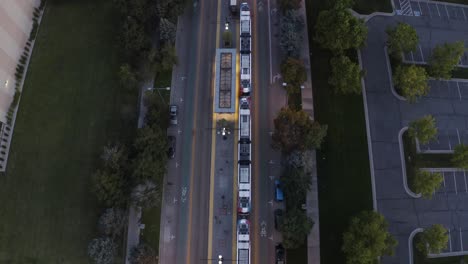 Overhead-aerial-view-of-a-cable-car-parked-picking-up-commuters-in-the-evening