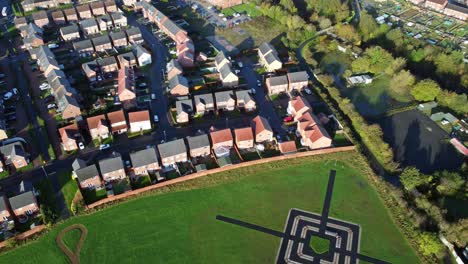Aerial-view-above-new-build-modern-housing-estate-tilt-down-to-target-pattern-in-field