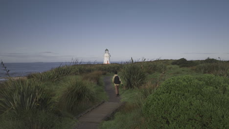 Woman-backpack-traveler-following-coastal-path-towards-Waipapa-Lighthouse