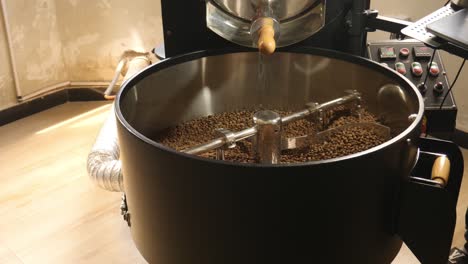 Coffee-roasting-machine-is-cooling-down-the-ready-beans-with-metal-arm