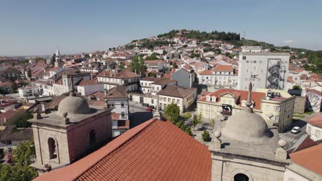 Aerial-drone-view-around-bell-towers-of-Castelo-Branco-Cathedral-with-cityscape-in-background,-Portugal