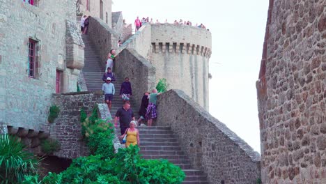 People-walking-down-stairs-at-Mont-Saint-Michel,-Normandy,-France