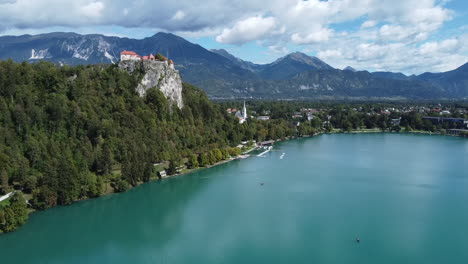 Drohnenaufnahme-Des-Wunderschönen-Bleder-Sees-In-Slowenien---Drohne-Nähert-Sich-Kirche-Und-Schloss-In-Der-Nähe-Des-Sees