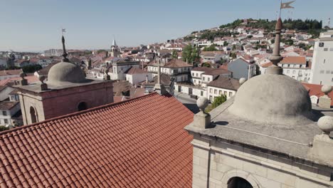 Aerial-orbiting-around-bell-towers-of-Castelo-Branco-Cathedral-with-cityscape-in-background,-Portugal