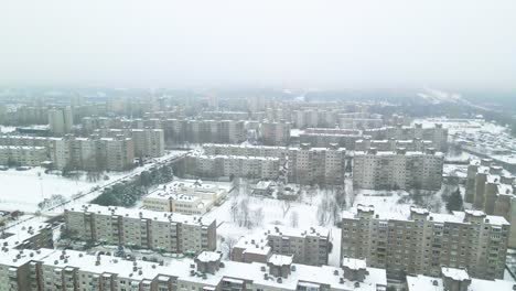 Aerial-view-of-apartments-houses-in-winter,-snowy-environment,-flying-above-apartment-houses,-soviet-Chernobyl-style-attached-buildings-in-Kaunas,-Lithuania,-paralax-shot