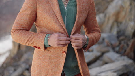 Closeup-of-a-man-hands-closing-his-suit-jacket-on-a-rocky-mountain-in-the-Italian-Alps