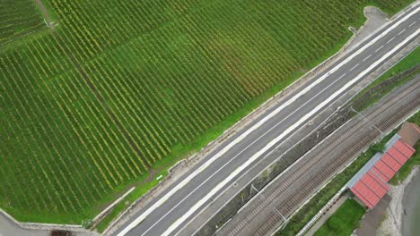 top-aerial-view-of-Lavaux-vineyards-next-to-a-road-with-cars-driving,-switzerland