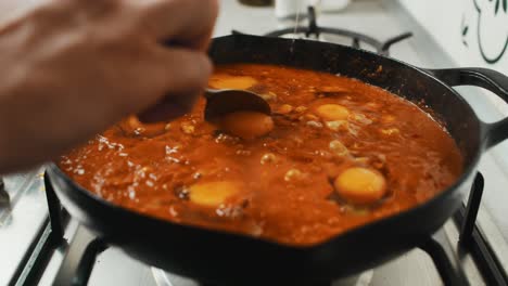 Chef-adds-egg-yolk-into-mashed-vegetable-mix-inside-deep-black-frying-pan