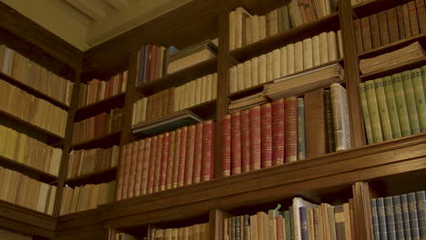 Panorámica-Sobre-Libros-Antiguos-En-Un-Estante-Alto-En-Una-Lujosa-Biblioteca-Privada