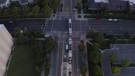 Top-down-aerial-view-of-a-public-transit-cable-car-passing-through-the-streets-at-night
