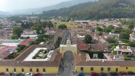 -Aerial-view-of-the-Santa-Catalina-arch-in-front-of-the-Iglesia-de-la-Merced-church,-in-Antigua,-Guatemala---ascending,-tilt,-drone-shot