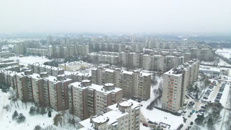 Aerial-view-of-apartments-houses-in-winter,-snowy-environment,-flying-above-apartment-houses,-soviet-Chernobyl-style-attached-buildings-in-Kaunas,-Lithuania,-camera-zooms-in,-flies-forward