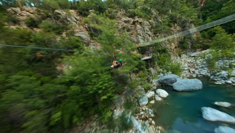 Active-woman-traveller-zip-lining-through-green-forest-and-mountain-river