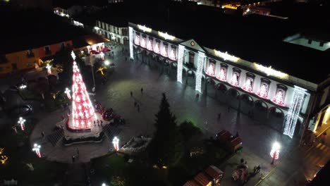 High-angle-shot-over-government-palace-in-the-small-Christmas-village-in-Central-Mexico-with-people-walking-around-decorated-with-beautiful-Christmas-decorations-at-night-time