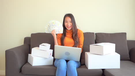 Asian-Woman-With-a-Laptop-and-Cash-Money-Celebrating-Winning-on-Lottery-or-Stock-Price-Rise,-Full-Frame