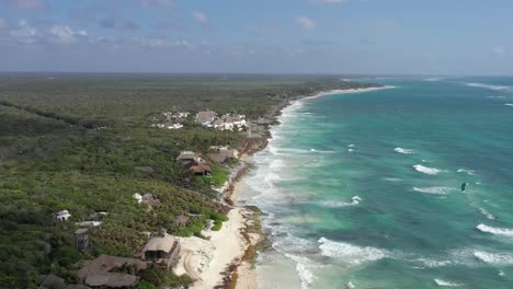 Sobrevuelo-Aéreo-Hermosa-Costa-Mexicana-De-Tulum-Con-Kite-Surf-En-El-Ondulado-Mar-Caribe-Durante-El-Día-Soleado---Hoteles-De-Lujo-Con-Playa-De-Arena-Privada