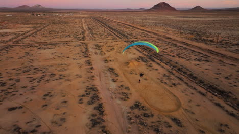 Volando-Detrás-De-Otro-Parapente-Motorizado-Sobre-El-Desierto-De-Mojave-Durante-Una-Impresionante-Puesta-De-Sol-Dorada