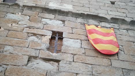 La-Senyera,-Flagge-Von-Katalonien,-Hängt-An-Der-Außenwand-Eines-Mittelalterlichen-Gebäudes-In-Spanien
